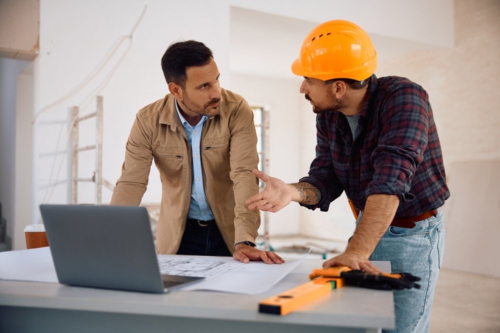 mid,adult,man,and,construction,worker,communicating,while,analyzing,blueprints